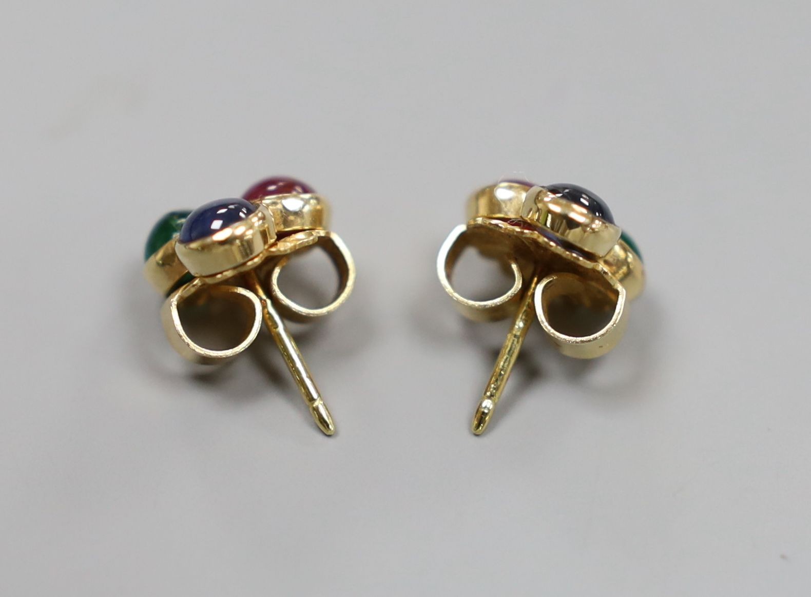 A modern pair of 750 and cabochon ruby, sapphire and emerald set three stone ear studs, 10mm, gross 3 grams.